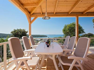 Terraza con mesa y sillas con vistas al mar bajo un cielo azul.