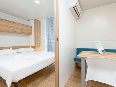 Habitación de hotel moderna con cama doble, escritorio y suelo de madera.