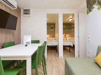 Camera d'hotel moderna con zona pranzo e camera da letto con due letti.