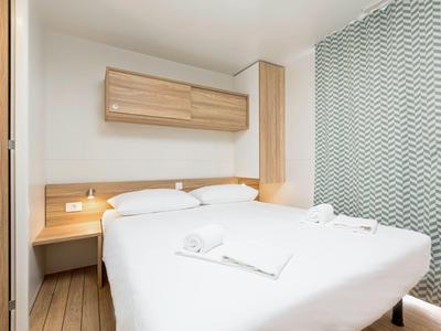 Habitación de hotel moderna con cama doble, muebles de madera y cortina estampada junto a ventana grande.