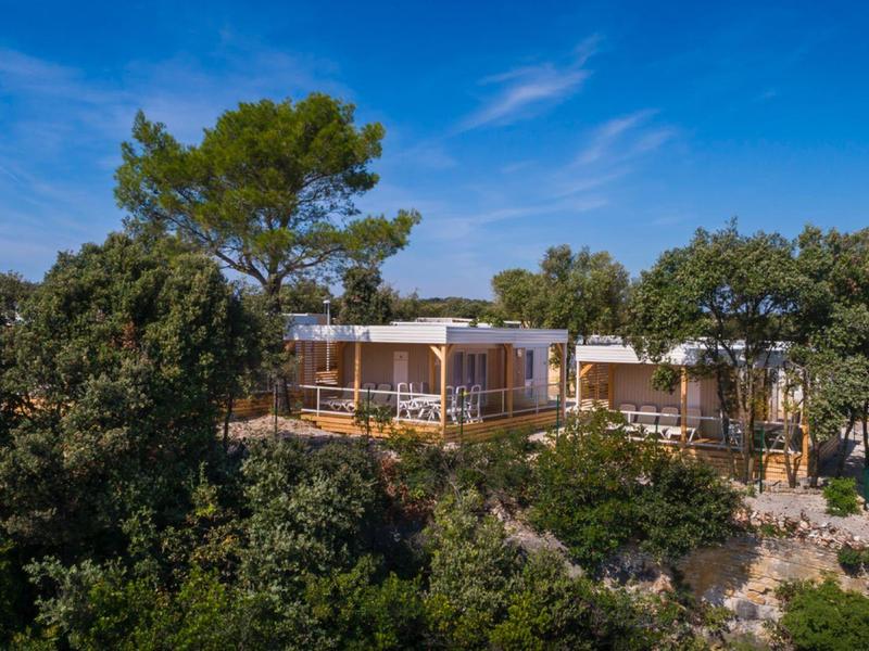 Casa vacanze moderna in un paesaggio boscoso sotto un cielo azzurro.