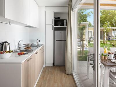 Kitchenette moderna con microondas y nevera, acceso a terraza con comedor exterior.