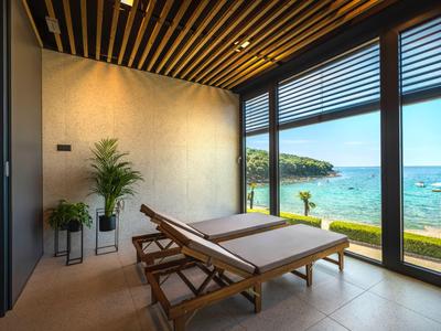Chambre moderne avec deux chaises longues et grande fenêtre donnant sur la mer.