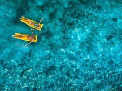 Zwei Menschen schwimmen in klarem, türkisfarbenem Wasser mit Schnorchelausrüstung.