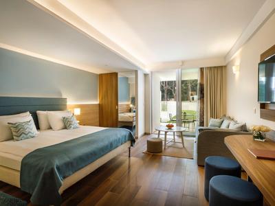 Modern eingerichtetes Hotelzimmer mit Doppelbett, Schreibtisch, Sofa und Balkon mit Blick ins Grüne.