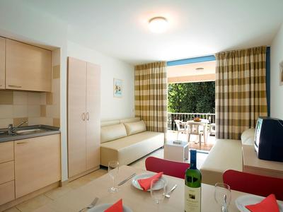 Espace de vie confortable avec kitchenette et terrasse dans une chambre d'hôtel.