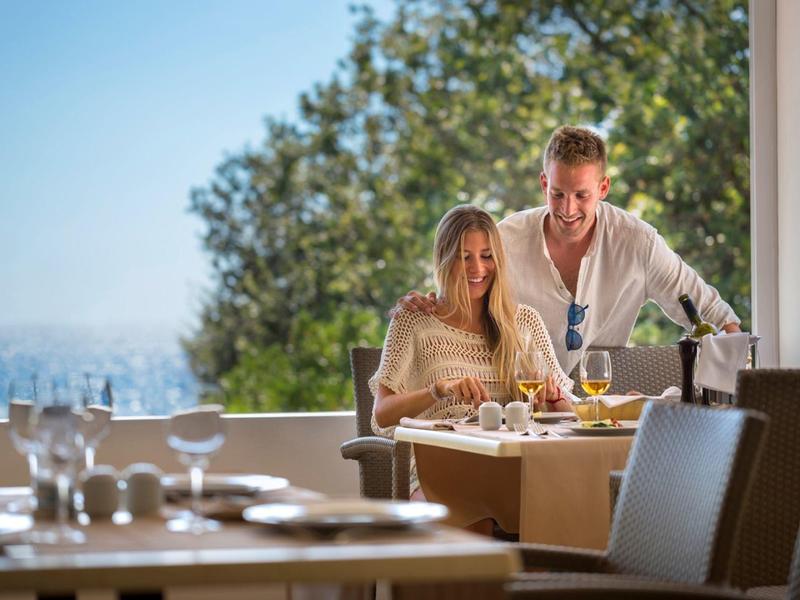 Couple dégustant le petit-déjeuner sur la terrasse avec vue sur la mer par temps ensoleillé.