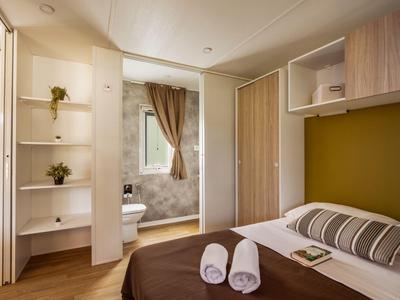 Cozy bedroom with double bed, towels, and attached bathroom in warm tones.