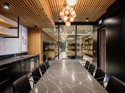 Nowoczesna sala konferencyjna z długim marmurowym stołem, wygodnymi czarnymi krzesłami i drewnianym sufitem z kulistymi lampami