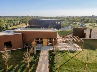 Modernes Gebäude mit Holzverkleidung und Pergola in ländlicher Umgebung unter klarem Himmel.