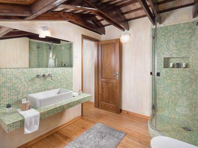 Nowoczesna łazienka z jasnymi zielonymi płytkami, drewnianym stropem i szklaną kabiną prysznicową