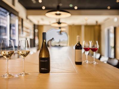 Butelki i kieliszki wina na długim drewnianym stole w eleganckiej restauracji.