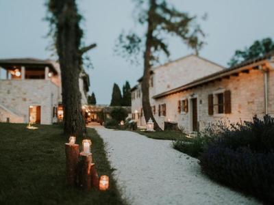 Oświetlona żwirowa ścieżka między kamiennymi budynkami i drzewami o zmierzchu