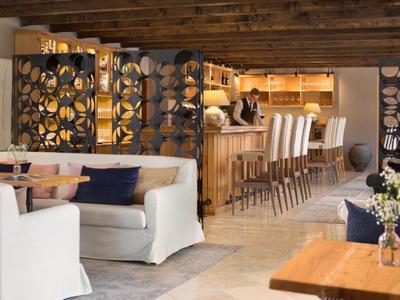 Przytulny salon hotelowy z białymi sofami i barem za dekoracyjnymi drewnianymi przegrodami.