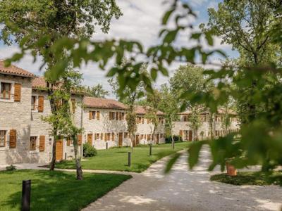 Bliźniak z kamienną elewacją obok wybrukowanej ścieżki i zielonego ogrodu.