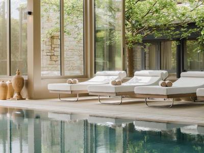 Wewnętrzna strefa basenowa z nowoczesnymi leżakami i dużymi oknami w jasnym pomieszczeniu