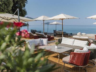 Strefa wypoczynkowa na zewnątrz z wygodnymi fotelami i parasolami z widokiem na morze.