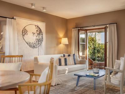 Przytulny salon z jasnymi meblami i dużymi oknami z widokiem na zielony ogród.