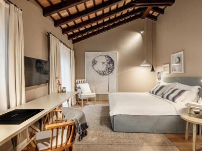 Przytulny pokój hotelowy z drewnianymi meblami, łóżkiem podwójnym i rustykalnymi belkami.