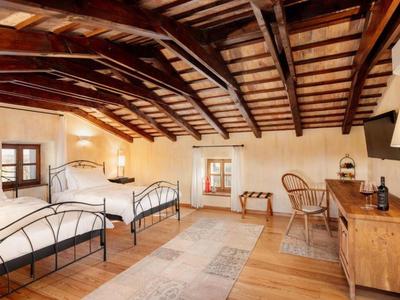 Przytulny pokój hotelowy z dwoma pojedynczymi łóżkami, drewnianym stropem i rustykalnym urokiem.