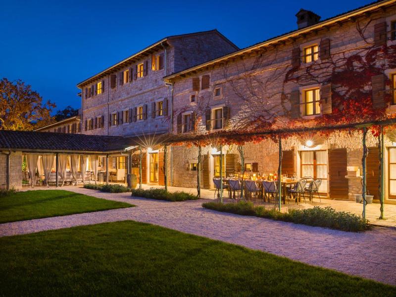 Oświetlony budynek hotelu z dziedzińcem i ogrodem o zmierzchu.