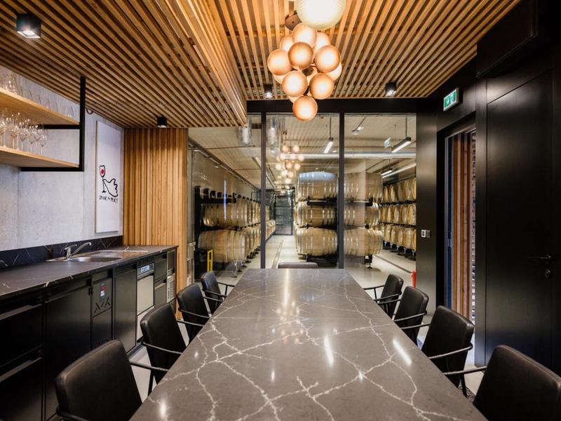 Nowoczesna sala konferencyjna z długim marmurowym stołem, wygodnymi czarnymi krzesłami i drewnianym sufitem z kulistymi lampami