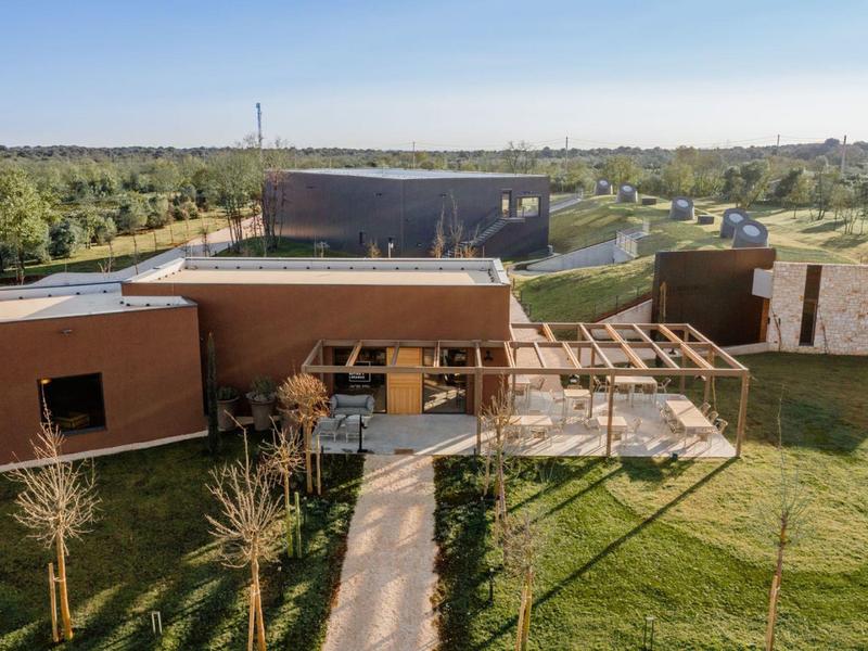 Nowoczesny budynek z drewnianym wykończeniem i pergolą w wiejskim otoczeniu pod czystym niebem.