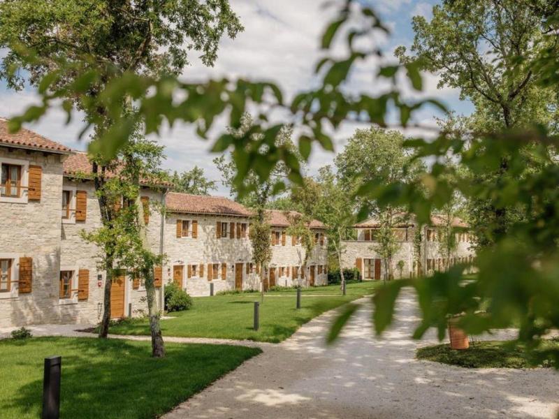 Rząd jasnych domków wakacyjnych z drewnianymi okiennicami wzdłuż brukowanej ścieżki i zielonego trawnika