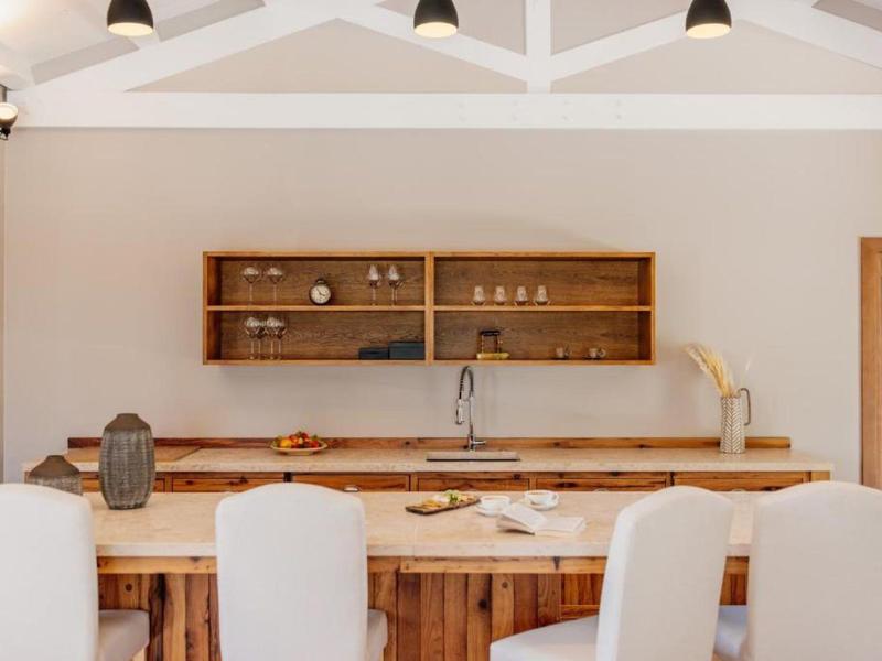 Nowoczesna kuchnia z drewnianym stołem i białymi krzesłami w jasnym pomieszczeniu.