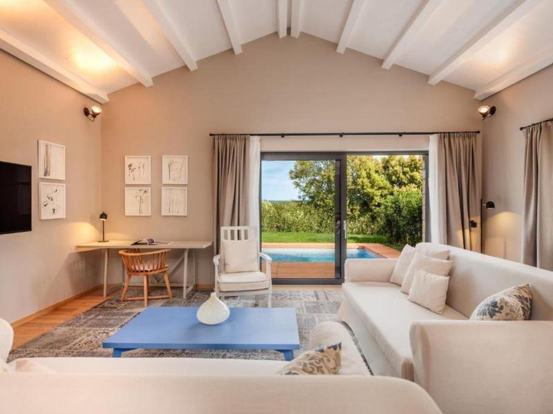 Przytulny salon z sofami, biurkiem i widokiem na basen na zewnątrz.