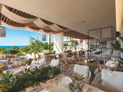 Otevřená jídelní oblast s prostřenými stoly s výhledem na bazén a moře