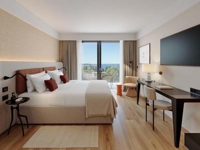 Modern hotel room with large bed, desk, and balcony with a view