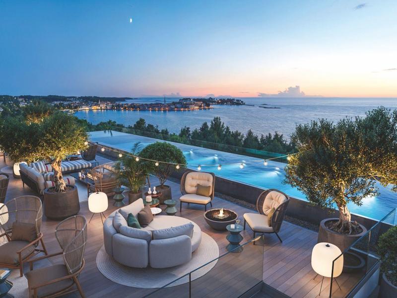 Luxury rooftop terrace with pool, modern seating, and sea view at sunset.