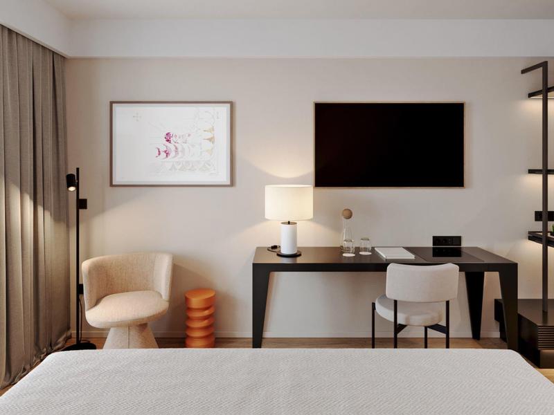 Modern hotel room with desk, chairs, and wall-mounted TV