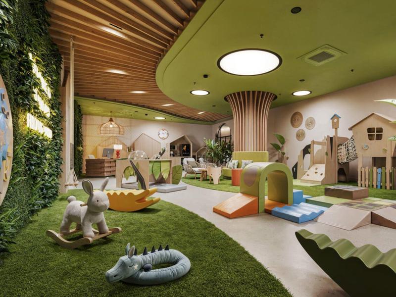 Interieur van een moderne, kleurrijke speelruimte voor kinderen met zacht tapijt en diverse speeltoestellen.