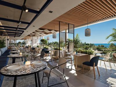 Moderna terraza de hotel con asientos y vista al mar en clima soleado.