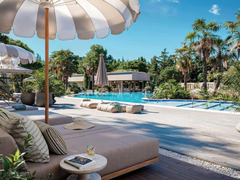 Ein luxuriöser Poolbereich mit Liegen, Sonnenschirmen und tropischen Pflanzen an einem sonnigen Tag.