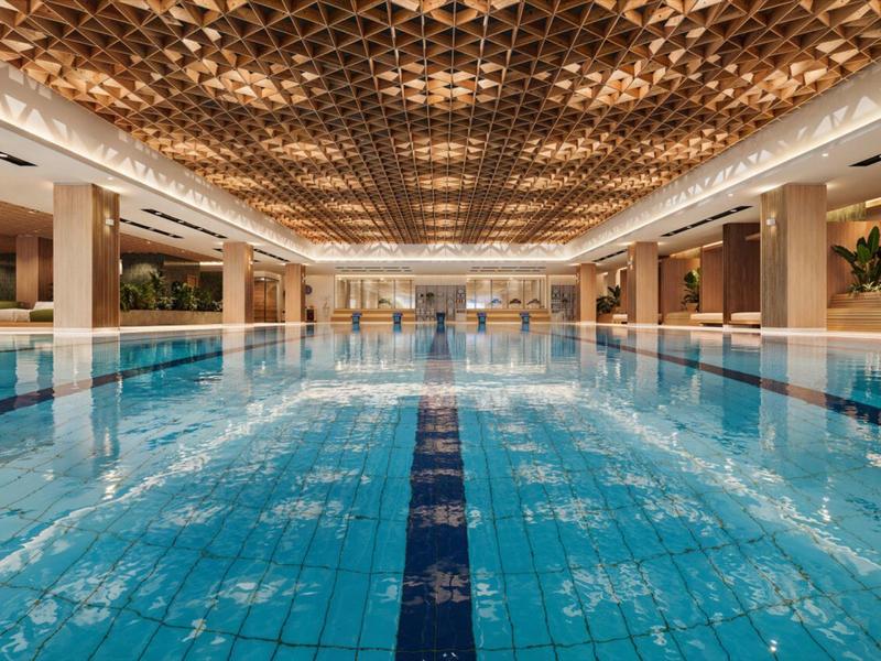 Duży basen kryty z niebieską wodą i dekoracyjnym sufitem w luksusowym hotelu