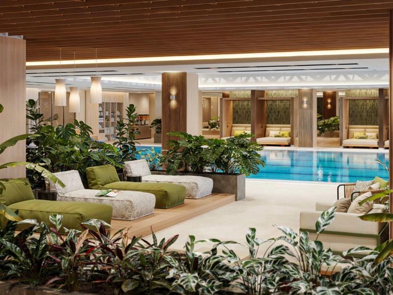 Przytulna przestrzeń wypoczynkowa z sofami i roślinami obok krytego basenu w hotelu.