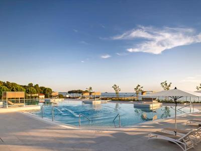 Großer Hotelpool mit Liegestühlen und Sonnenschirmen bei klarem Himmel