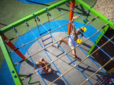Bovenaanzicht van een klimrots met kinderen die een net beklimmen.