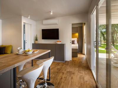 Moderner Wohnbereich mit Holzboden, Esstisch, weißen Stühlen und Zugang zu Terrasse mit Gartenblick.