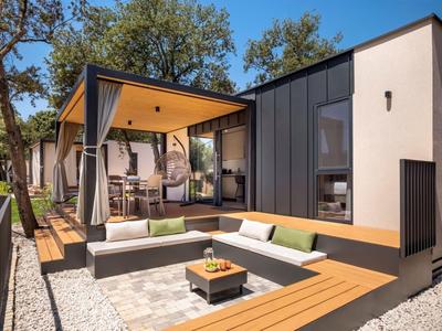 Moderner Hotelbereich mit offener Terrasse, Holzdekor und gepolsterten Sitzgelegenheiten im Freien.