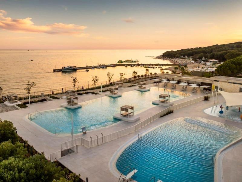 Luxe hotelzwembad met infinity-ontwerp en uitzicht op zee bij zonsondergang.