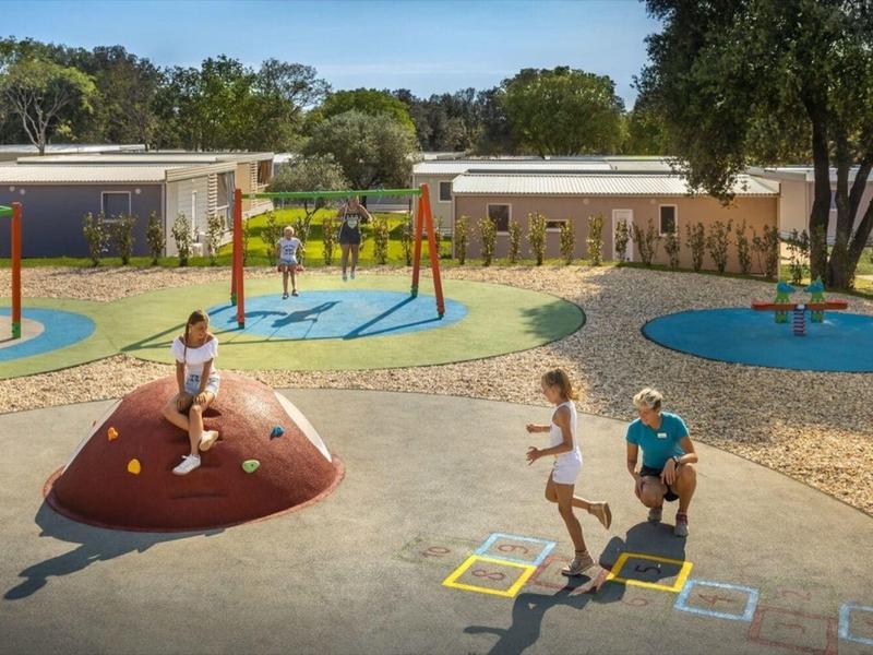 Kinderen spelen op een kleurrijke speelplaats buiten met verschillende klim- en balanceertoestellen.