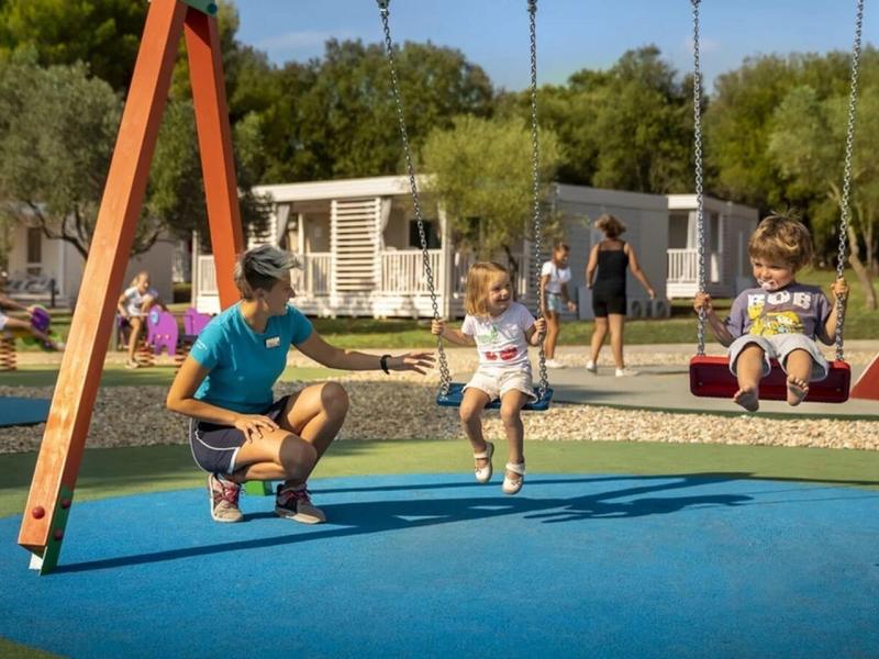 Vader en kind schommelen samen op een moderne speeltuin bij zonnig weer.