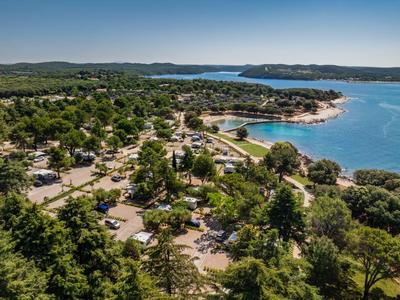 Veduta aerea di un campeggio boscoso sul mare con vista sulla costa e sulla baia.