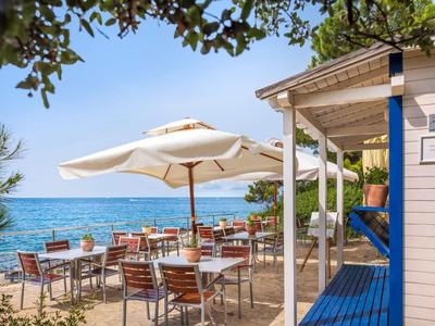 Terrazza di un ristorante sulla spiaggia con tavoli, sedie e ombrelloni vicino al mare.