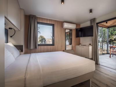 Nowoczesny pokój hotelowy z łóżkiem podwójnym, oknem, telewizorem i dostępem do tarasu z widokiem na ogród.