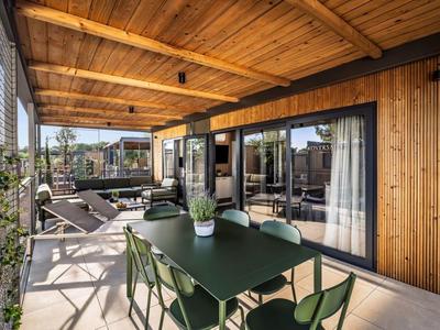 Nowoczesny balkon z zielonym stołem jadalnym, krzesłami i drewnianą okładziną w pokoju hotelowym.